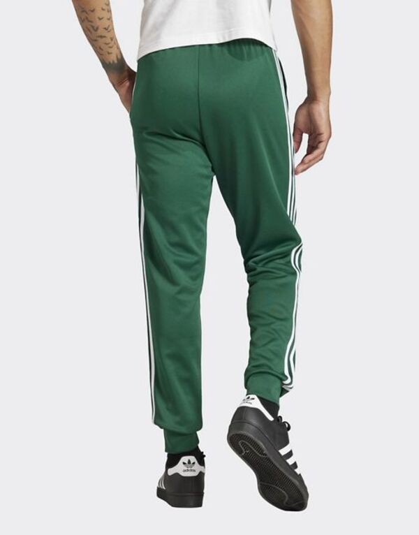 アディダス メンズ カジュアルパンツ ボトムス adidas Originals Superstar trackpants in collegiate green MID GREENの通販は