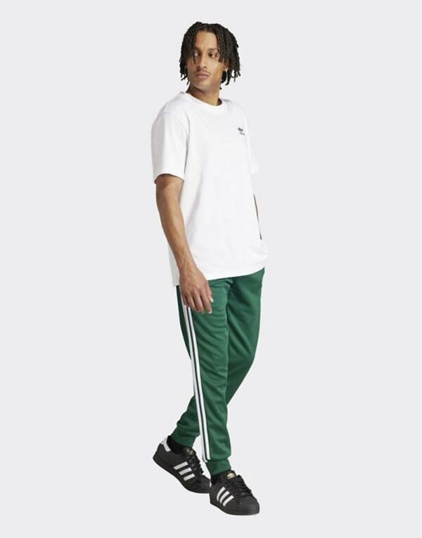 アディダス メンズ カジュアルパンツ ボトムス adidas Originals Superstar trackpants in collegiate green MID GREENの通販は