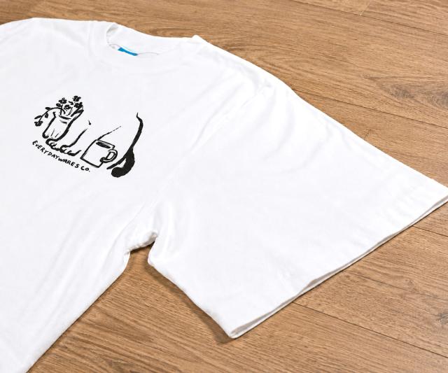 平置きされたTシャツと5.5オンスUSAコットン生地のクローズアップ。柔らかさと耐久性を兼ね備えた素材感。