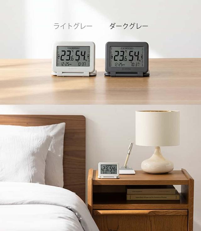 RHYTHMのデジタル温湿度計付き時計。上部はカラー比較で、ライトグレーとダークグレーの2色が並ぶ。下部は使用シーンの提案で、ベッドサイドの木製ナイトテーブルに、ライトグレーの温湿度計が、白いテーブルランプや本、ペンスタンドと一緒に置かれている。