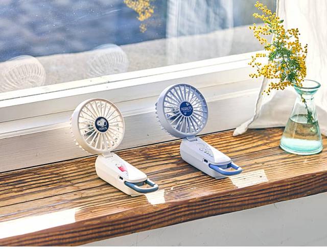 ファン部分を折り曲げて卓上扇風機（デスクファン）として使用できるシルキーウィンドモバイル4スヌーピーモデル。日差しが差し込む窓辺に置かれたホワイトとブルーの2台。