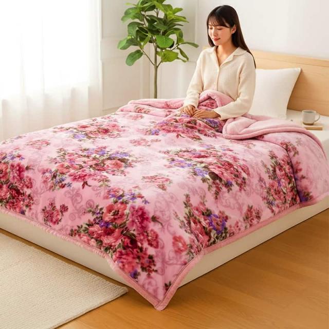 花柄ピンクのテイジン掛け毛布にくるまりベッドに座る女性